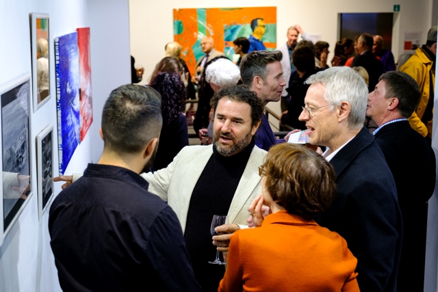 Cuban artist Luis Camejo talks about his work with guests at the opening night